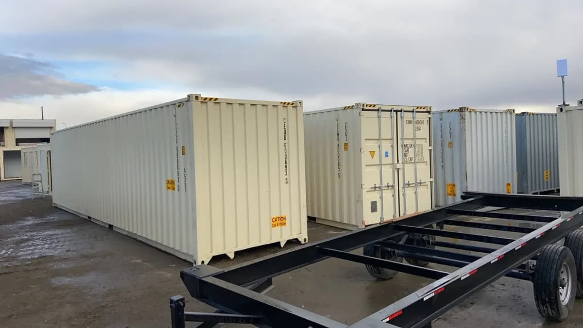 Shipping containers in a storage lot with a container trailer in the foreground