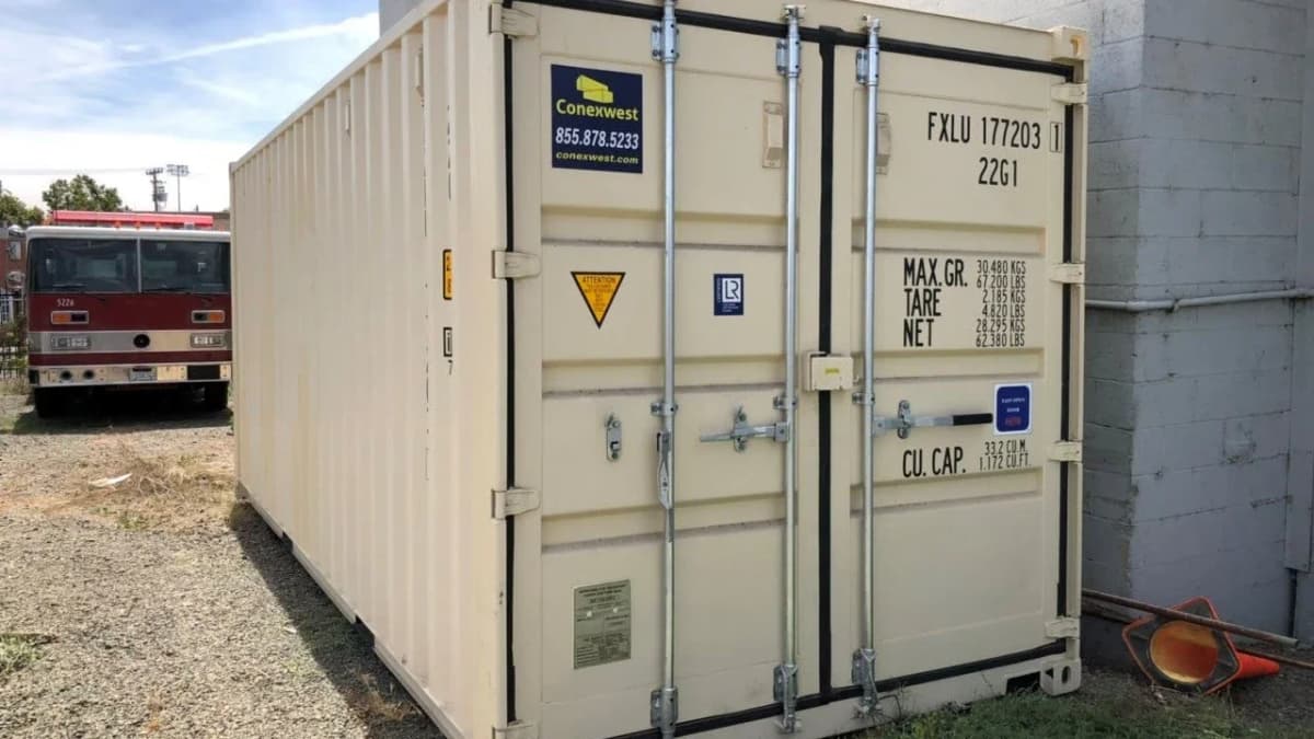 Image of a Conexwest branded shipping container in front of a fire tender and next to a building.