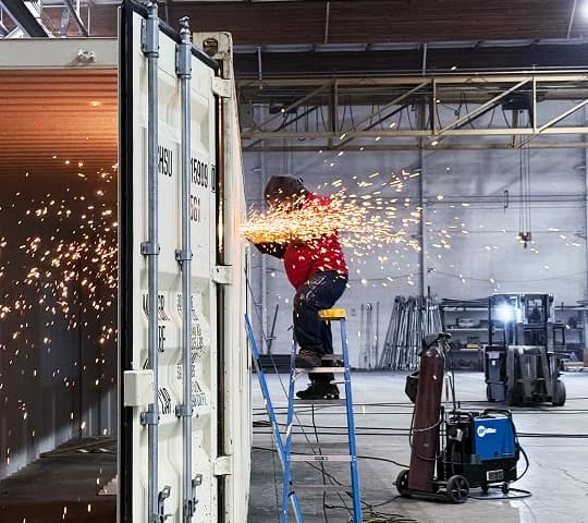 Welder working on a shipping container inside a Conexwest facility