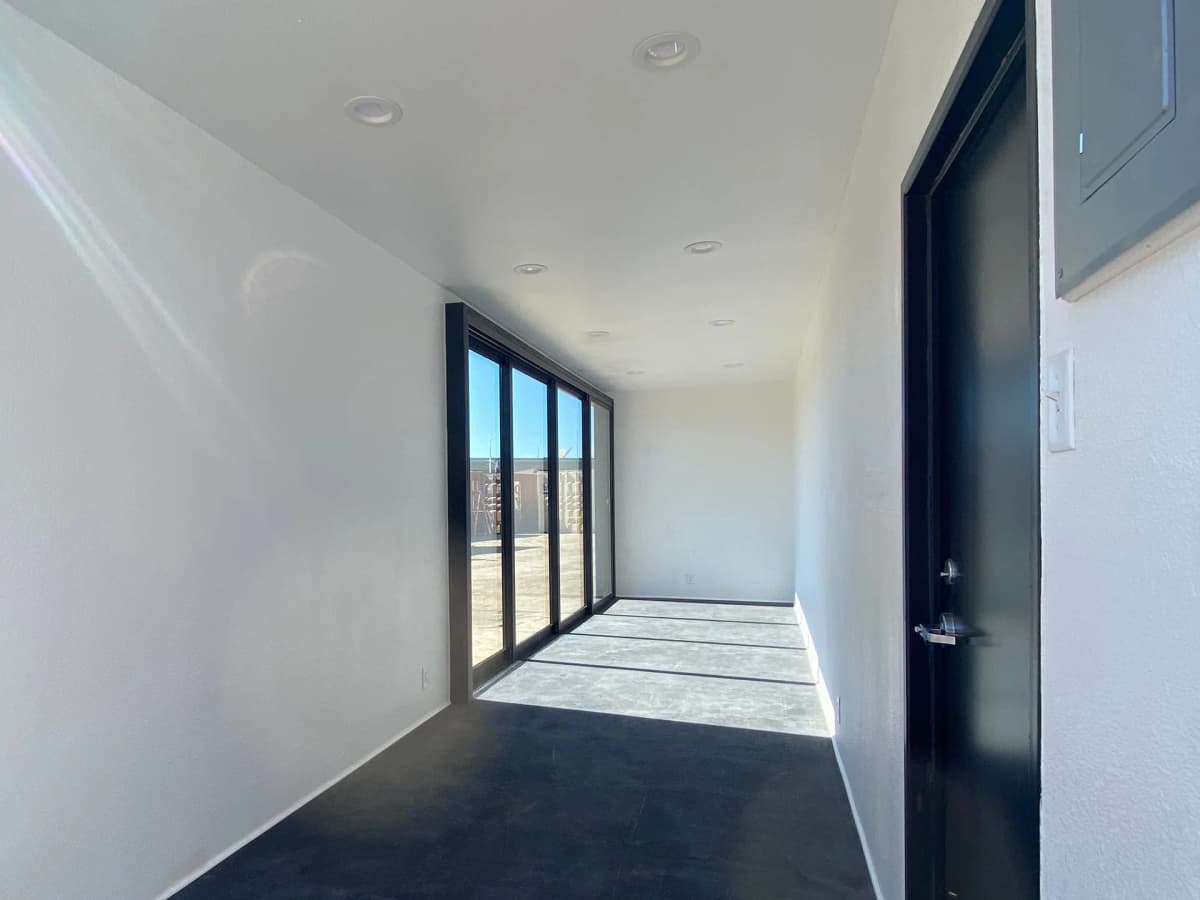Custom matte black container storefront interior with rear access door and finished walls