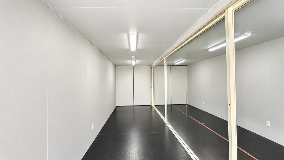 Finished Allied Environmental container office interior with white wall panels dark flooring and LED ceiling lights