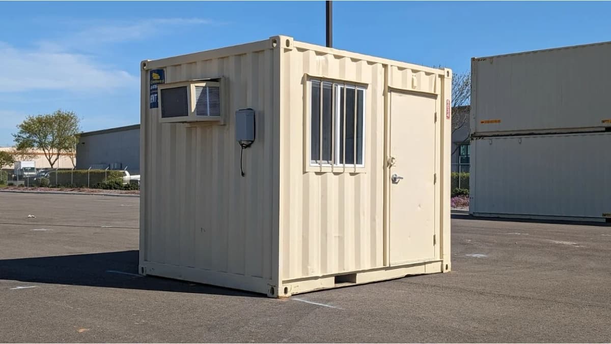 10ft container with a window, door, and wall-mounted air conditioning unit, placed in an outdoor industrial lot