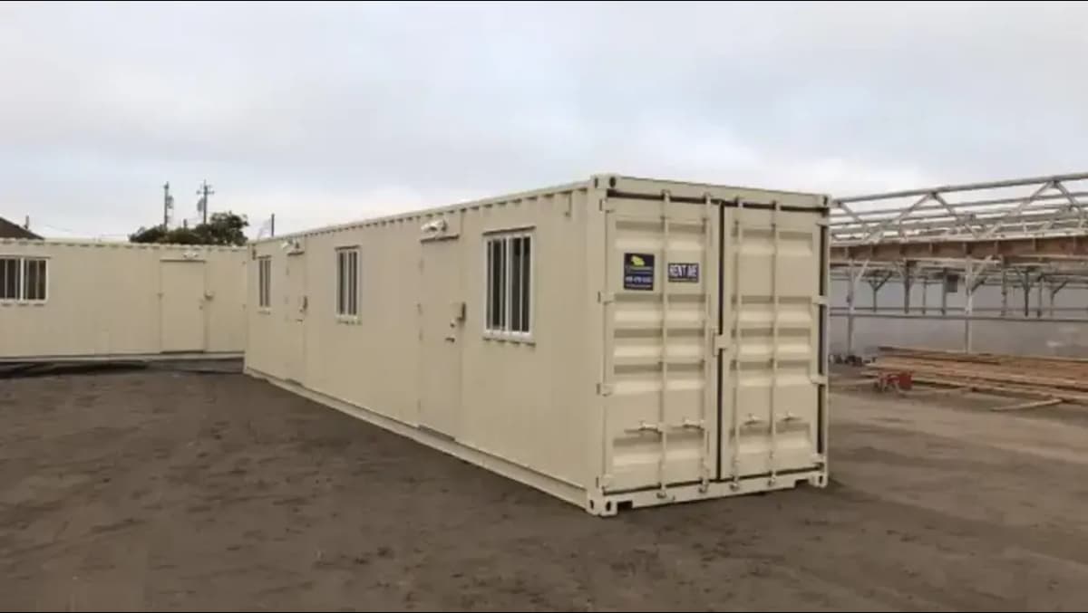 40-foot shipping container converted into a mobile office unit with multiple slide windows and air conditioning units.
