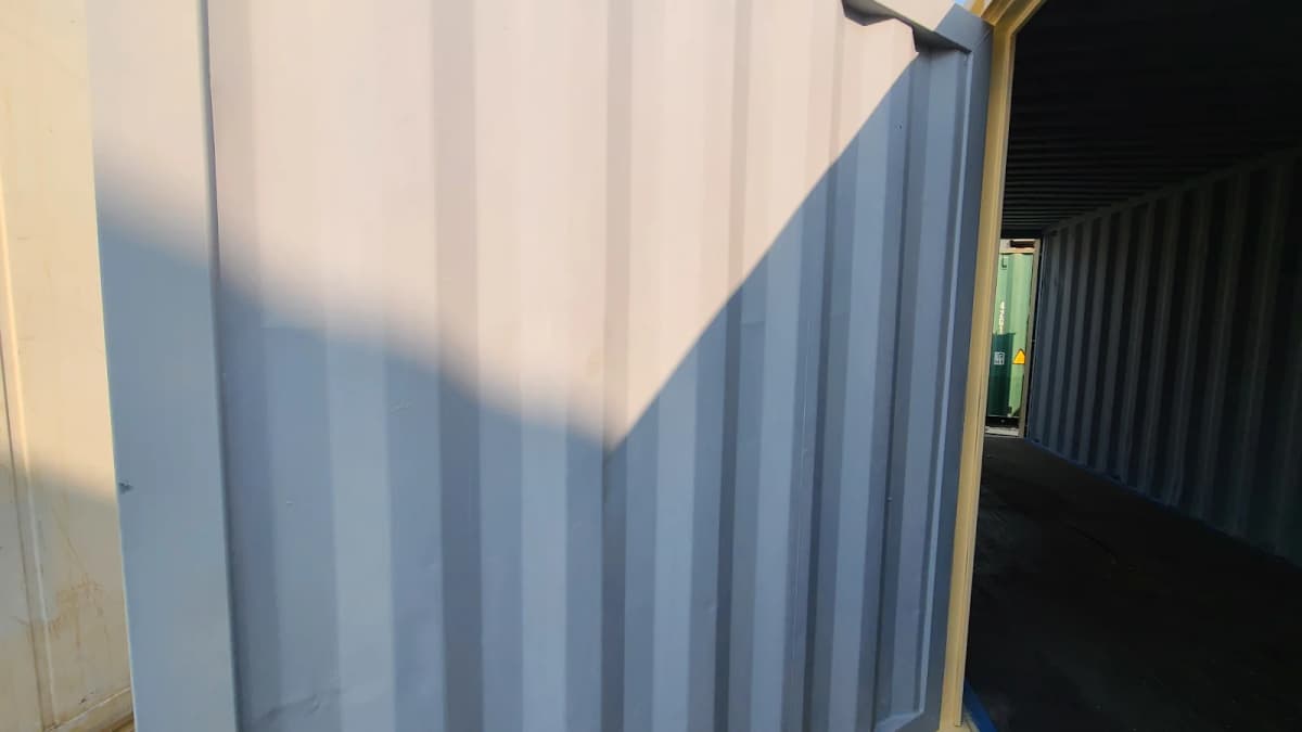 Close-up shot of a corrugated metal door in sunlight and opening into an empty container