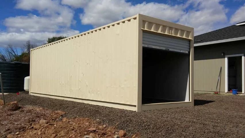 A large shipping container placed on leveled ground with an open roll-up door