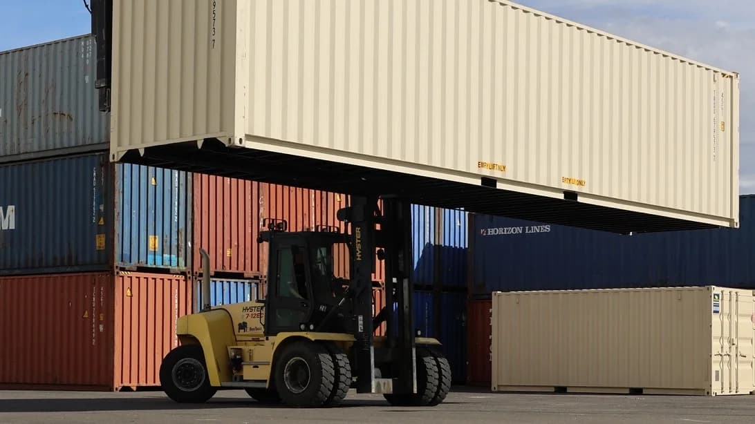 Forklift lifting shipping container onto stack