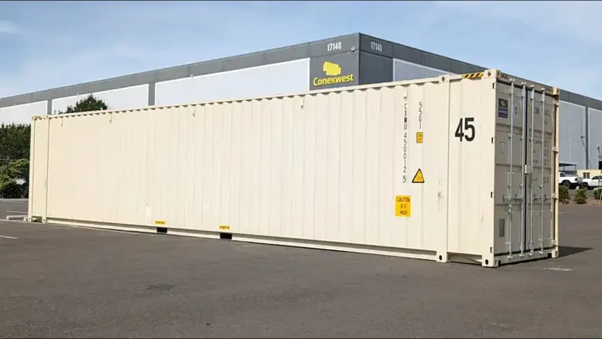A white shipping container in front of a Conexwest facility.