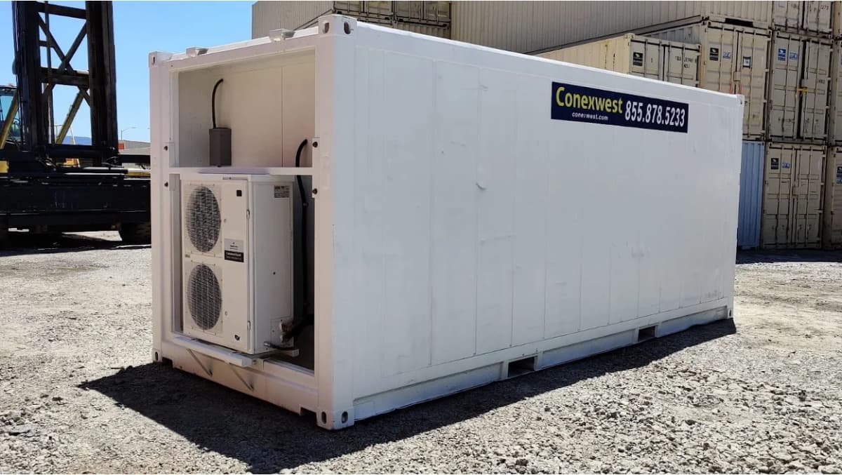 A white shipping container modified with HVAC units installed