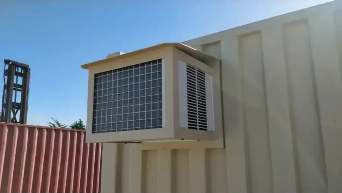 Close-up of a wall-mounted air conditioning unit installed on the exterior of a beige Conexwest shipping container.