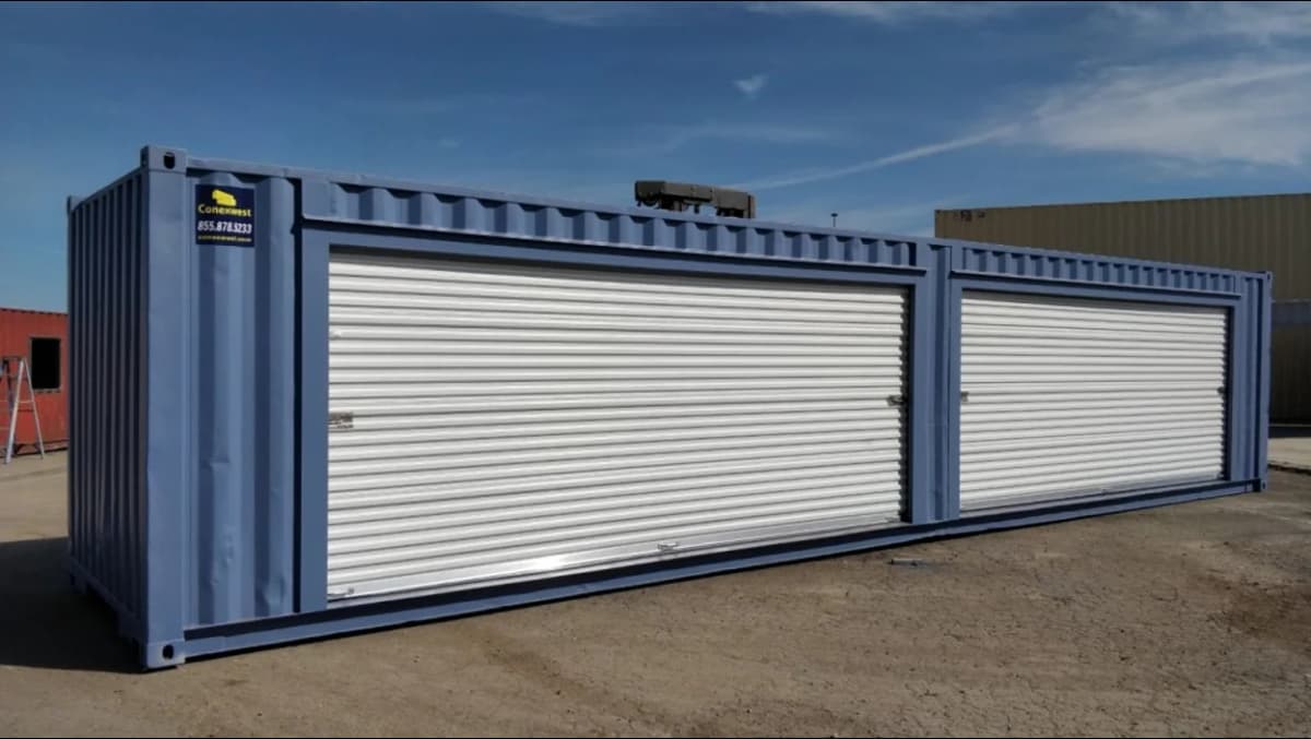 Conexwest modified blue shipping container with two large white roll-up doors, situated on a concrete surface.