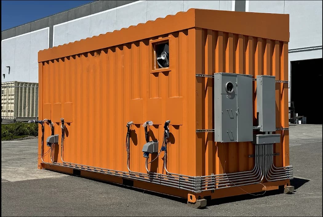 Exterior of an orange shipping container featuring multiple mounted electrical panels and ventilation equipment.