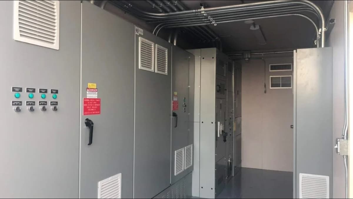 Interior view of a container's mechanical room showing electrical control panels.