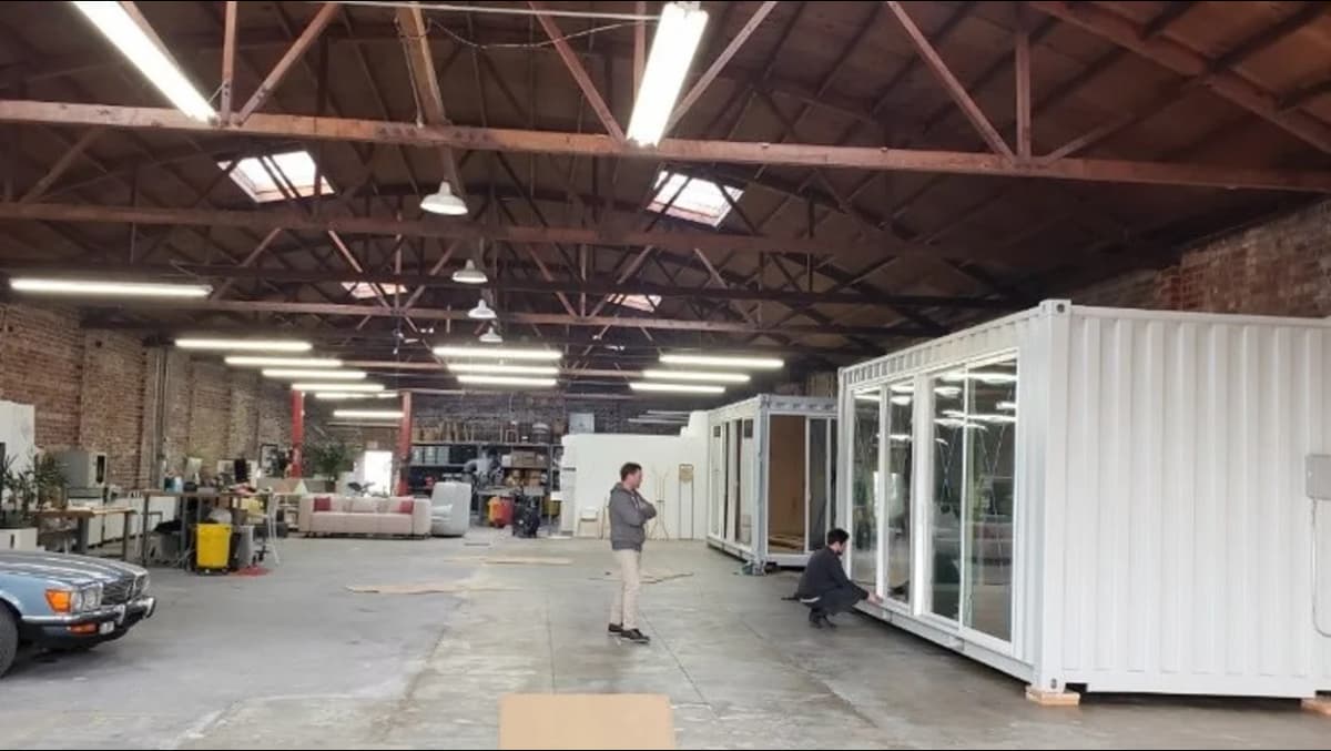 Interior view of a warehouse containing white modified shipping containers with windows and doors.