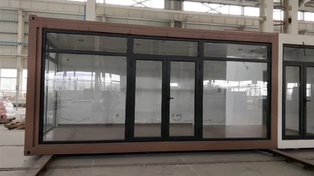 Modern shipping container cafe structure with large glass windows and double glass doors