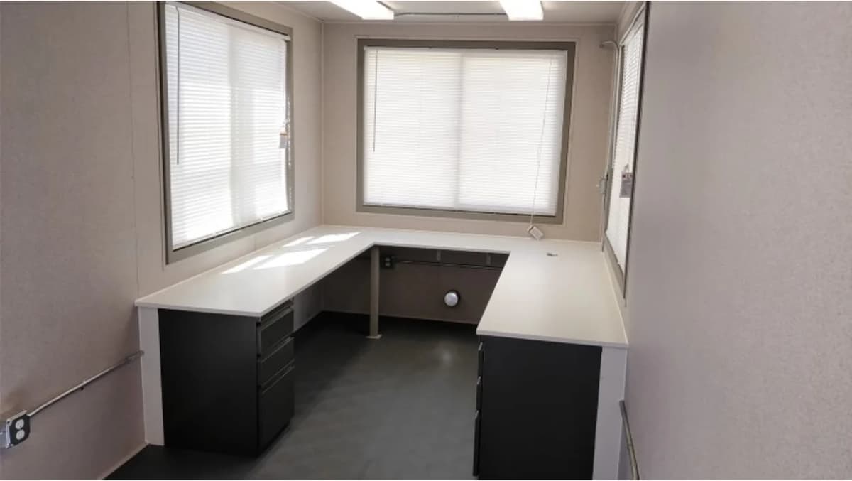 The interior of a storage container with desk space, windows, and electrical plugs.