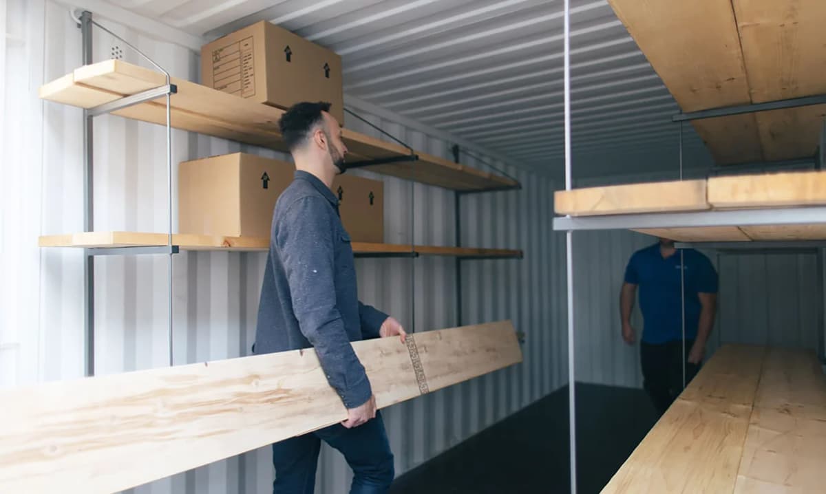 Two men setting up a shipping container shelf.