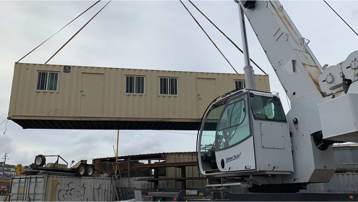 A shipping container apartment hanging on a crane