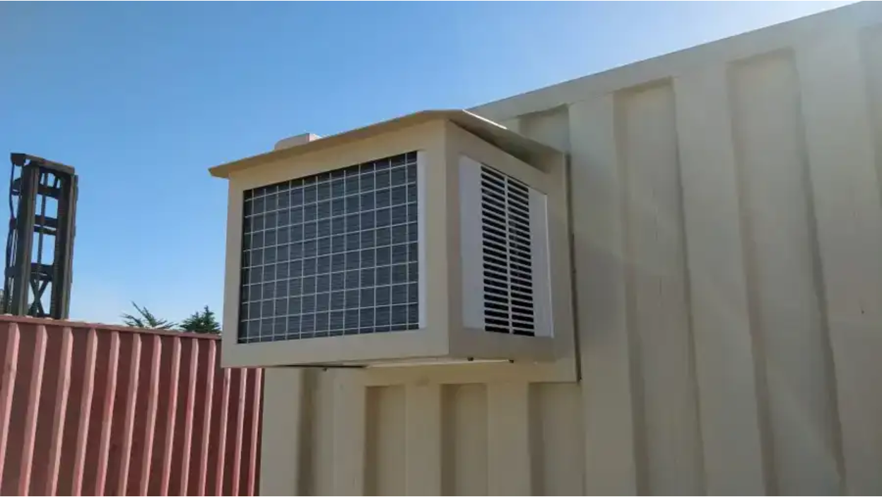 Close-up of a wall-mounted air conditioning unit installed on the exterior of a beige Conexwest shipping container.