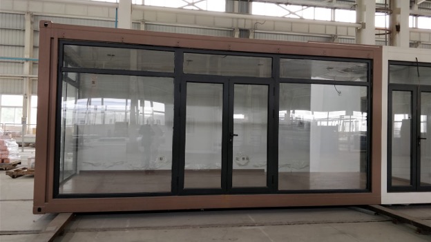 Glass-walled container unit with black frame and brown exterior.