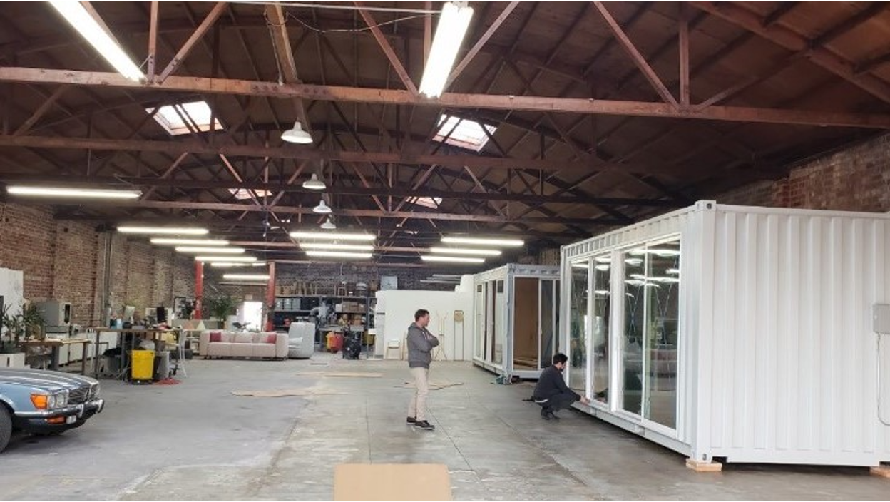 Interior view of a warehouse containing white modified shipping containers with windows and doors.
