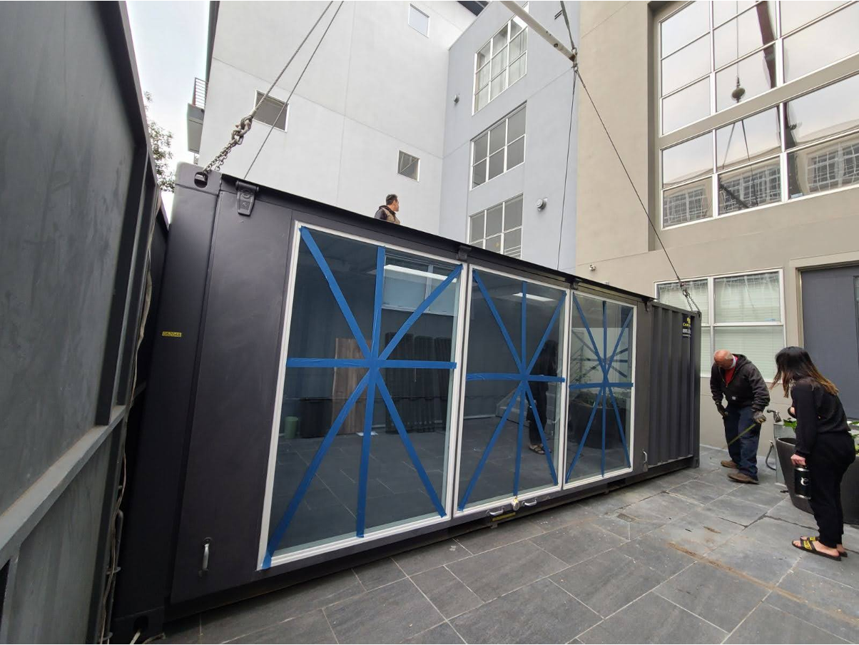 The Conexwest team working on a shipping container with glass walls. 